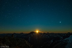 View of the moon rising as well as the stars and satellites.